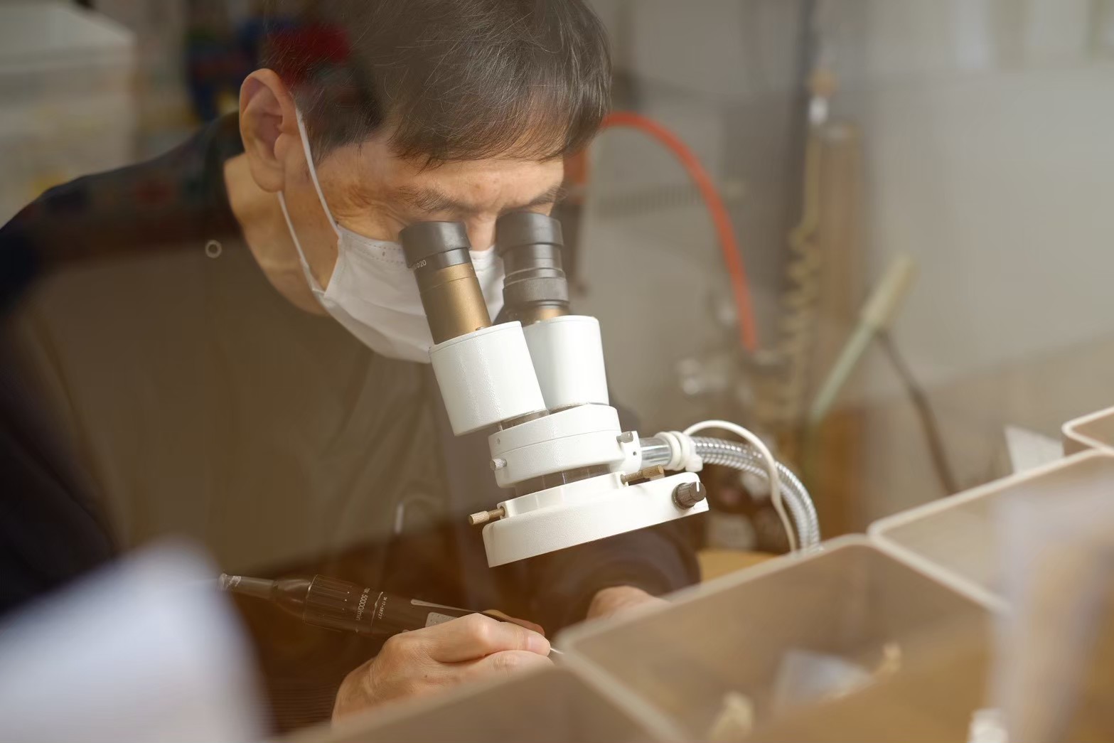 顕微鏡で拡大しながら被せ物を調整する歯科技工の作業風景
